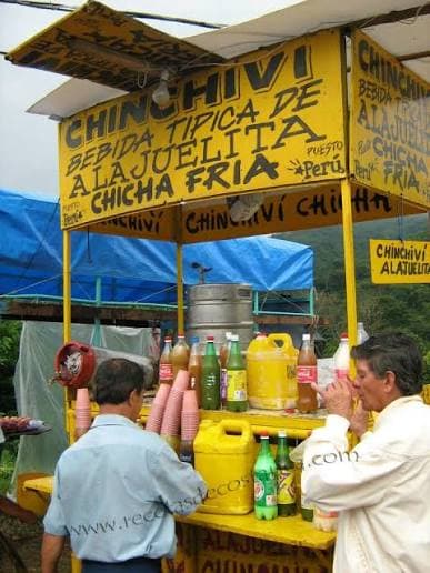 A yellow roadside stand in Alajuelita selling chinchiví and chicha fría by the bottle
